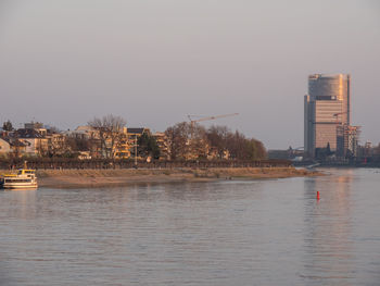 Scenic view of river by buildings against clear sky