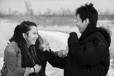 Cheerful siblings playing on field during winter