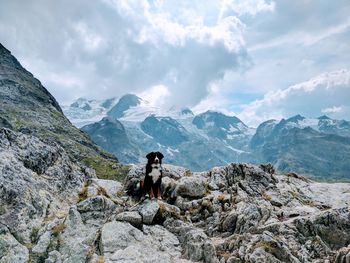 Man sitting on rock in mountains against sky