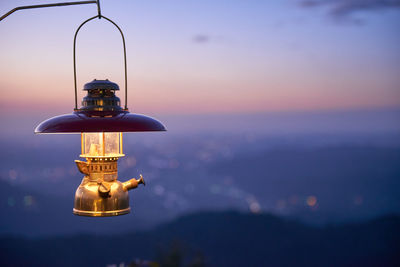 Close-up of illuminated lamp post against sky during sunset