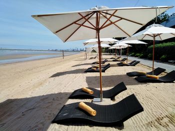 Tilt image of beach umbrellas by sea against sky