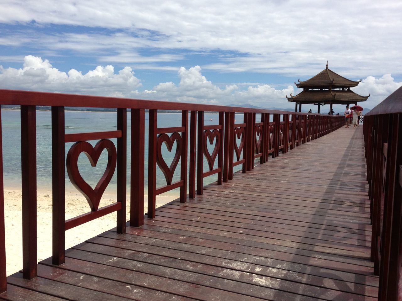 sea, built structure, sky, tourism, pier, text, architecture, western script, travel destinations, water, railing, tranquil scene, building exterior, famous place, international landmark, vacations, tranquility, scenics, cloud - sky, outdoors, footpath, the way forward, tourist resort, boardwalk, history, torii gate