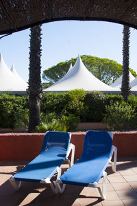 Lounge chairs on passage with trees and tents in background