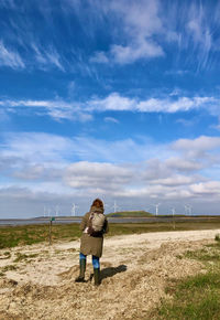 Rear view of woman standing on field against sky