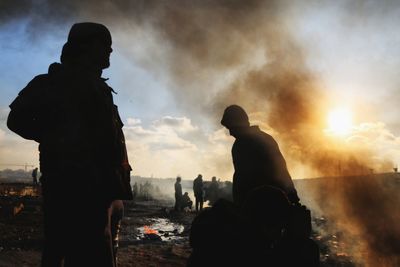 Silhouette people standing by volcanic landscape emitting smoke