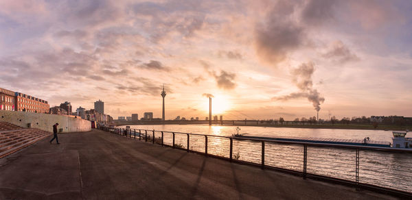 Bridge over river against sky in city during sunset