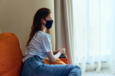 Side view of woman using mobile phone while lying on bed at home