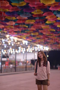 Smiling young woman standing against building