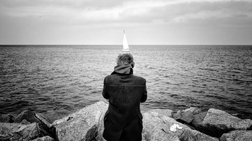 Rear view of woman looking at sailboat in sea