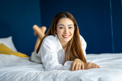 Portrait of young woman sitting on bed at home