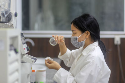 Vietnamese woman scientist checking laboratory glass flask to make an experiment in the laboratory