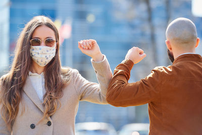 Man and woman wearing mask bumping elbow