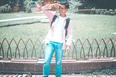 Smiling man shielding eyes while standing in park