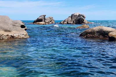 Rocks in sea against blue sky