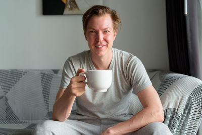 Portrait of smiling man sitting on bed at home