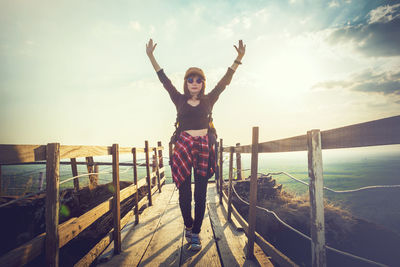 Full length of woman standing by railing against sky