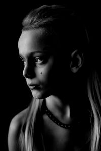 Close-up of girl looking away against black background