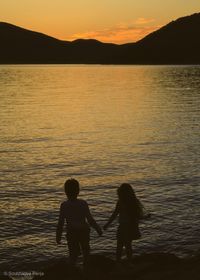 Silhouette people on beach against sky during sunset