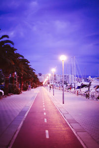 Illuminated street light against sky at night