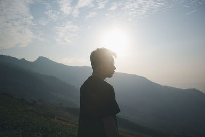 Side view of man looking away standing against mountain