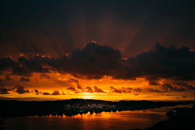 Scenic view of lake against cloudy sky during sunset in town