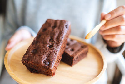 Close-up of hand holding cake on table