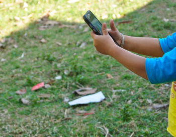 Midsection of child holding mobile phone in field