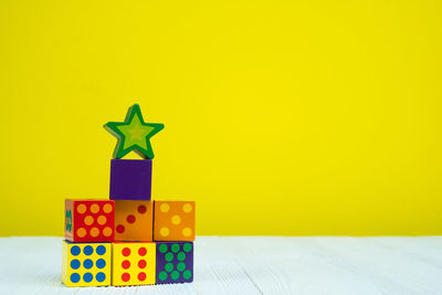 Stack of toys on table against yellow background