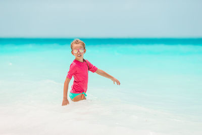 Full length of happy boy on beach against sky