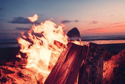 Panoramic view of bonfire on shore against sky during sunset