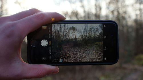 Midsection of person photographing through mobile phone