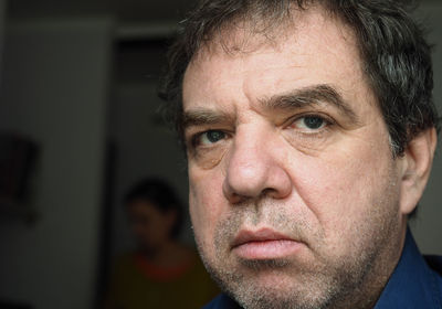 Close-up portrait of mature man with woman standing in background