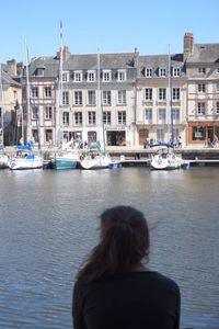 Rear view of woman on boat moored at harbor against clear sky