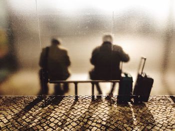 Rear view of two men sitting at bus stop