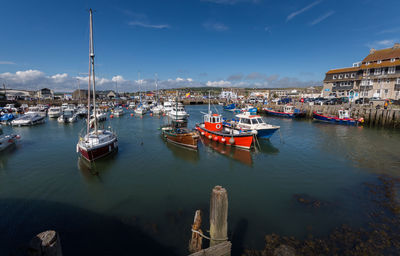 Boats moored at harbor against sky