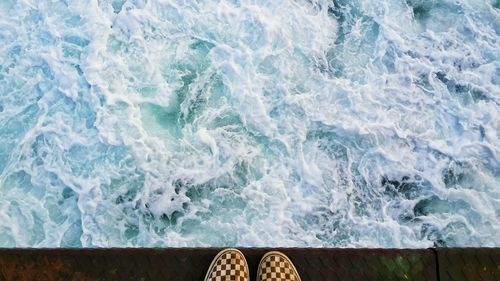 Footwear on edge of pier over sea