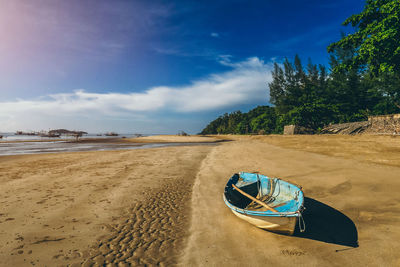 Boat moored on beach against sky