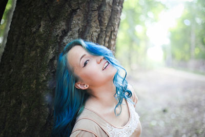 Portrait of young woman against tree trunk