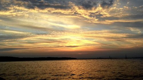 Scenic view of sea against dramatic sky during sunset