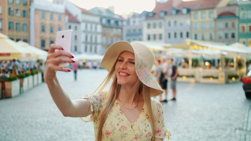 Side view of woman wearing hat standing in city