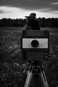 Close-up of man photographing on field against sky