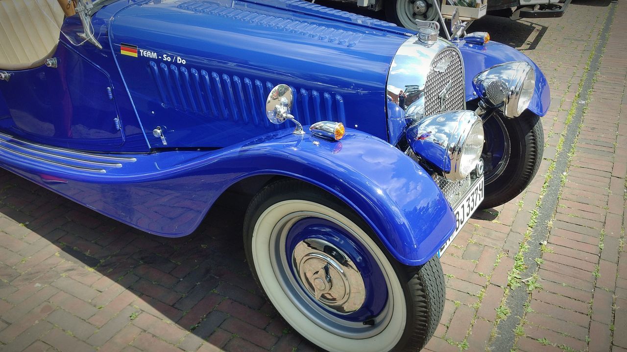 CLOSE-UP OF BLUE CAR ON THE ROAD