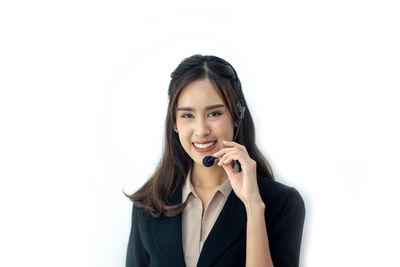 Portrait of smiling young woman standing against white background