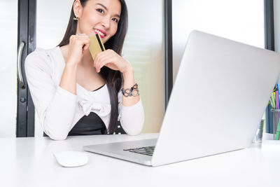 Young woman using phone while sitting on table