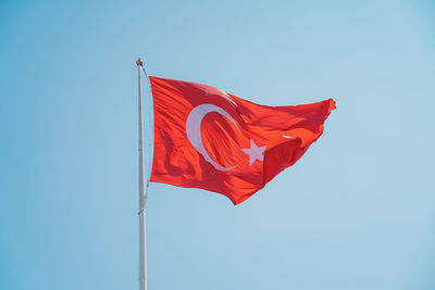 Low angle view of flag against clear blue sky