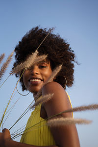 Portrait of a young black woman wearing yellow dress holding grass