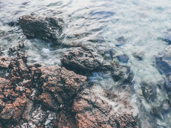 High angle view of sea water flowing on rocks