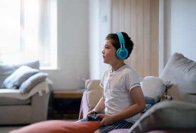 Young woman using mobile phone while sitting on bed at home