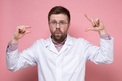 Portrait of man with arms raised standing against gray background