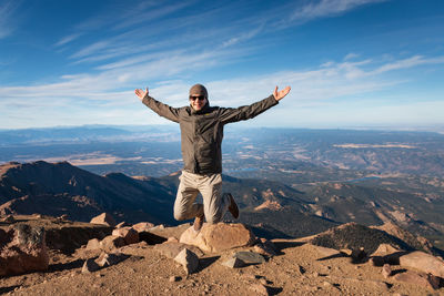 Full length of man jumping in the air and enjoying beeing on top of pikes peak, colorado against sky